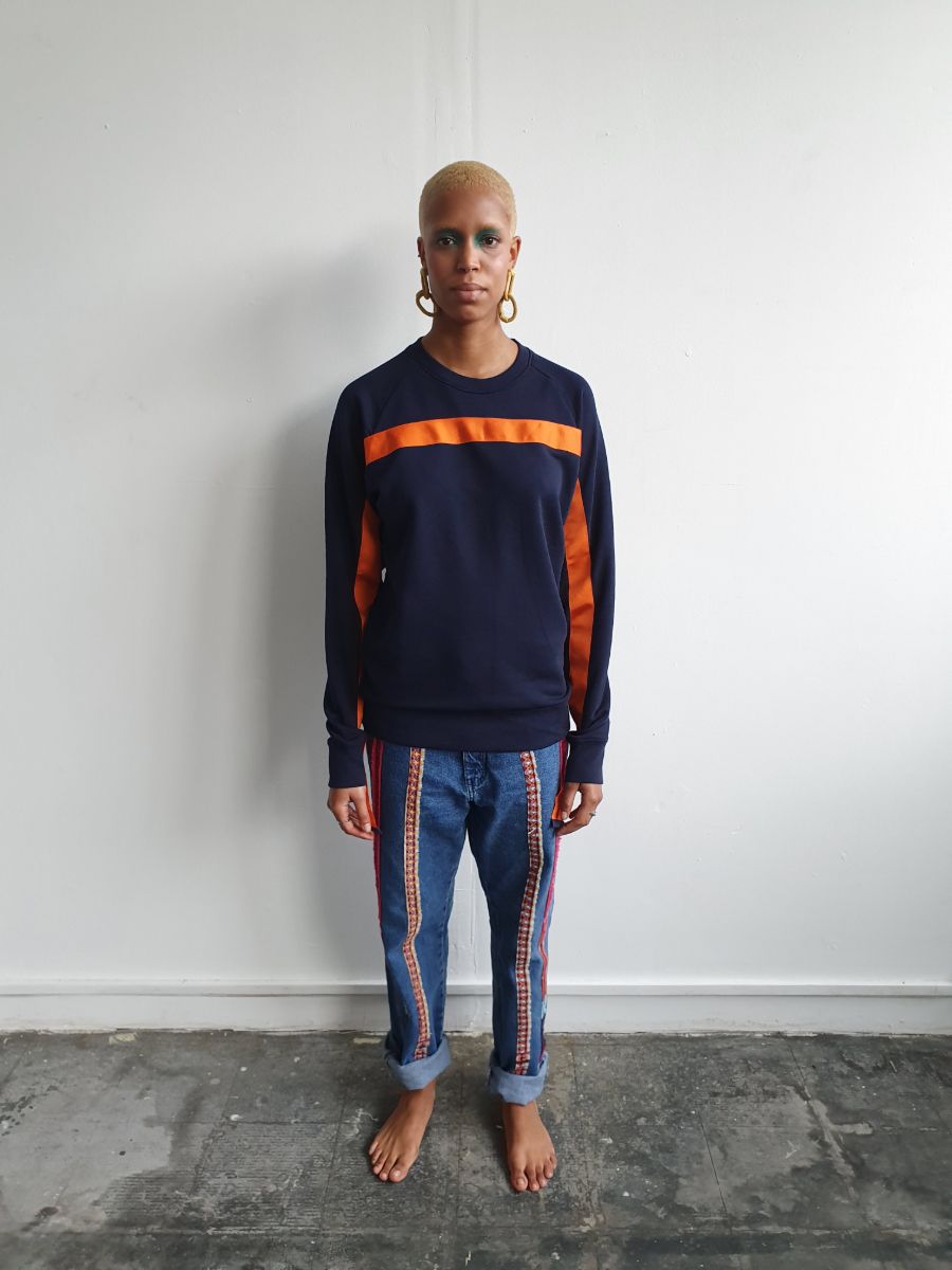 100% Gots certified organic cotton jumper in navy with an orange stripe across the chest & down the arms. Made by sustainable clothing brand Fanfare Label.