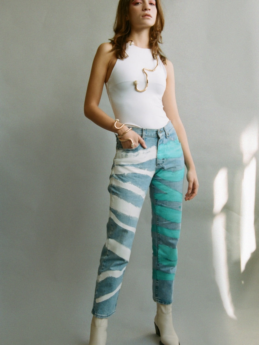 Fanfare Label sustainable women’s clothing brand UK. Our upcycled jeans are high-waisted, blue denim and made from recycled denim. We decorate every jean with a white & blue paint design.