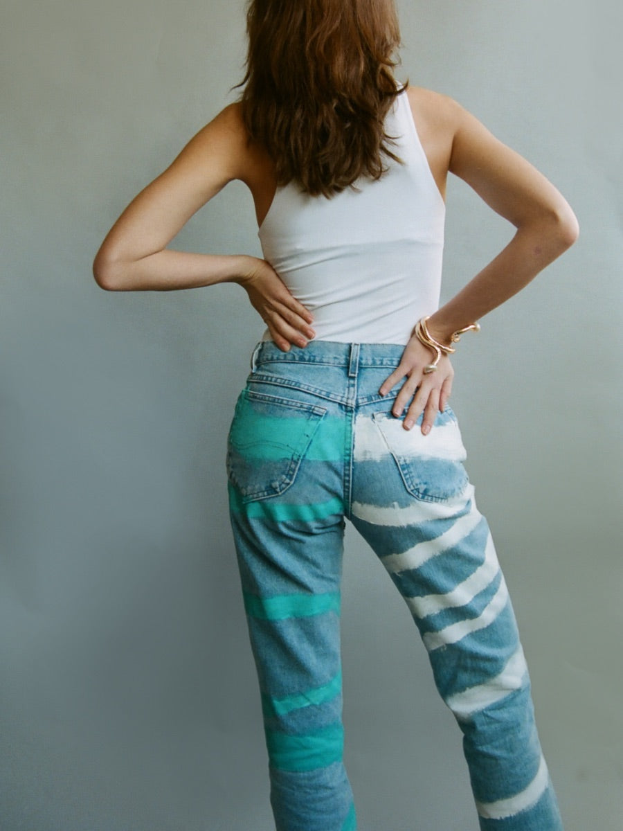 Fanfare Label sustainable women’s clothing brand UK. Our upcycled jeans are high-waisted, blue denim and made from recycled denim. We decorate every jean with a white & blue paint design.