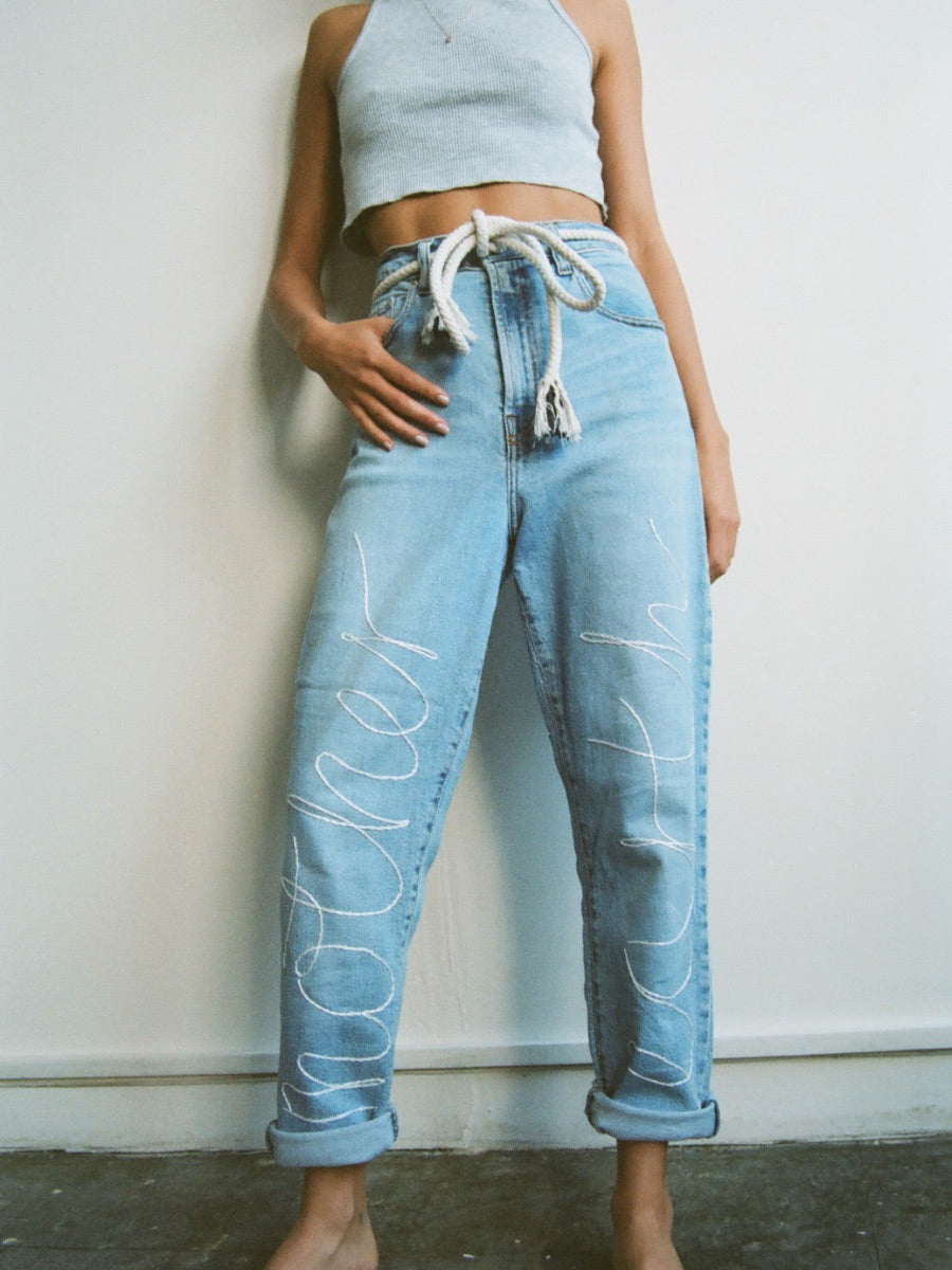 Upcycled jeans embroidered with the words 'Mother Earth'. A one-of-a-kind designer piece handmade in the UK by sustainable womenswear brand Fanfare in our ethical London factories.