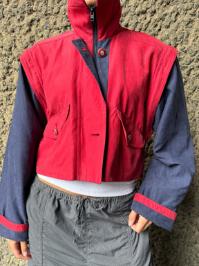 Upcycled red and navy waterproof short coat with removable sleeves, this jacket can also be worn as a gilet. Crafted by Fanfare artisans in our sustainable London-based factories.