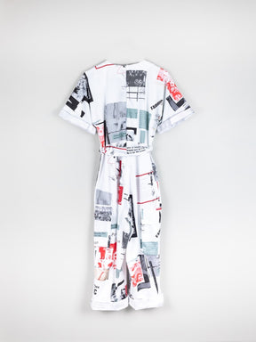 White based red & black printed jumpsuit, short sleeved with a belt. This printed white jumpsuit has sustainability activist messaging and is made by ethical clothing brand Fanfare Label