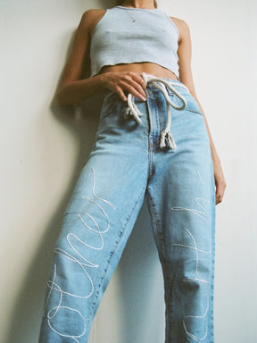 Upcycled jeans embroidered with the words 'Mother Earth'. A one-of-a-kind designer piece handmade in the UK by sustainable womenswear brand Fanfare in our ethical London factories.