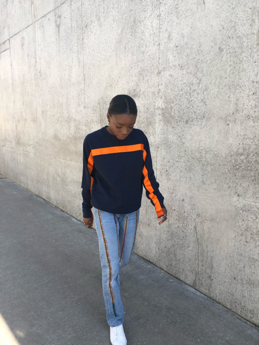 100% Gots certified organic cotton jumper in navy with an orange stripe across the chest & down the arms. Made by sustainable clothing brand Fanfare Label.